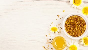 Honey and bee pollen with beautiful flower on white wooden desk Free Photo