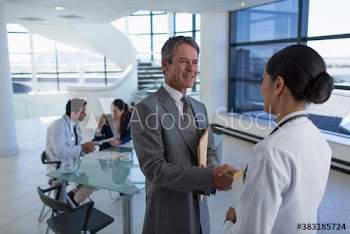 Hospital administrator shaking hands with doctor in meeting