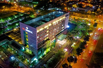Hospital Beside Vehicle Park and Road at Night