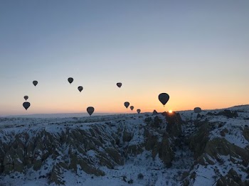 hot air balloon flying over snow capped mountain during golden hour