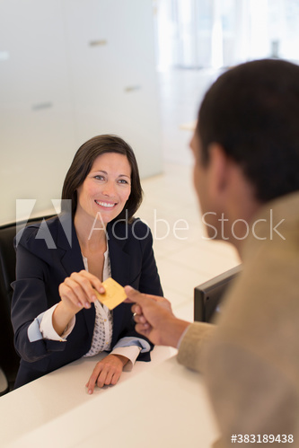 Hotel receptionist taking credit card from businessman