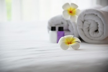 Hotel towel and shampoo and soap bath bottle set on white bed with plumeria flower decorated - relax vacation at the hotel resort concept Free Photo