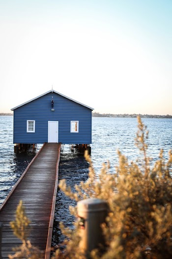 House With Dock on Body of Water Under Blue and White Sky