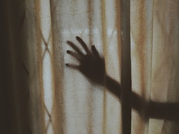 Human Hand Behind Brown Curtain