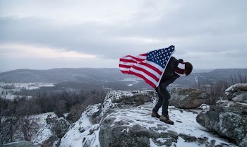 human holding a American Flag on the mountain