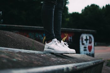 Human Standing on the Ground and Wearing White Nike Sneakers