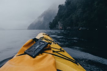 I did this Kayak Tour of the Milford Sound on a recent trip to New Zealand with Urban Armor Gear. After racing a colleague directly across the sound (about 1/2 mile), I pulled my camera out while resting and waiting for the rest of the group to catch up. 

The kayak was narrow and would easily tip so every movement on the kayak was tedious. Here I balanced my phone while taking a picture of the fog and light rain which gave the fiordlands an eerie feeling. Due to the lack of light, the only thing color that really stood out was my kayak and dry bag.
