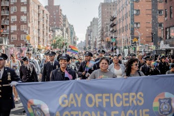 I was walking around at Pride 2019 in New York to portrait interesting people and scenes. 

All of a sudden I was in the front of this Gay Officers parade which was such a joy to watch. I went for the middle to capture both the banner and all the happy and proud officers standing up for themselves. 