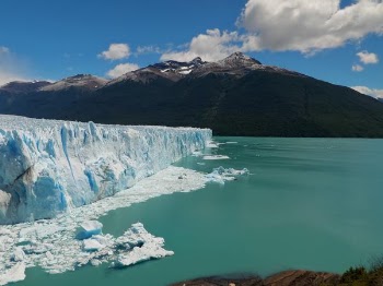 ice berg near mountain under cloudy sky