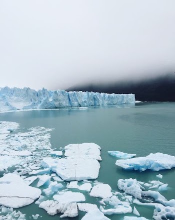 iceberg on body of water under cloudy sky
