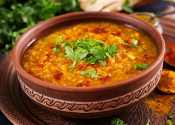 Indian dhal spicy curry in bowl, spices, herbs, rustic black wooden table Free Photo