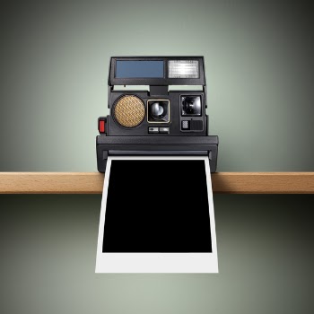 Instant camera on the shelf with a blank photo coming out.