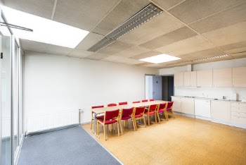Interior of a White Room With a Long Table and Red Chairs