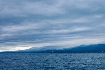 Island Across Body of Water Under Cloudy Sky