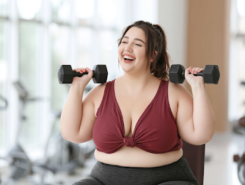 Joyful Plus-Size Woman Exercising with Dumbbells in Modern Gym