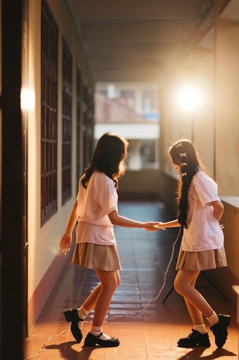 Joyful Schoolgirls Jumping Rope in Sunlit Corridor
