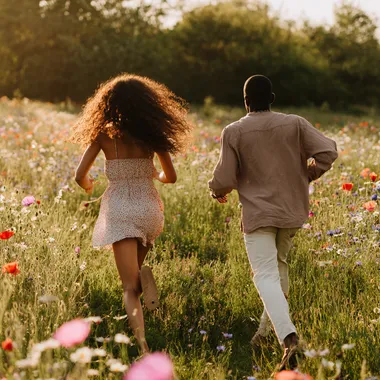 Joyful Young Black Couple Running Through Wildflower Meadow