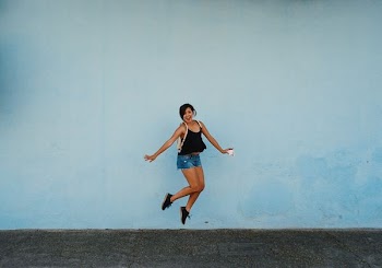jumping woman on gray ground under white cloud blue skies