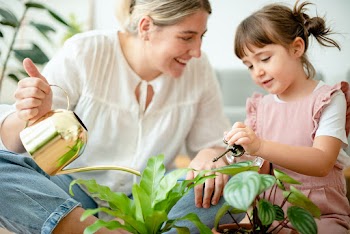 Kid watering potted plants with mom at home | Free stock photo | High Resolution image