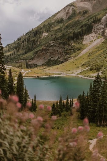 Lake Near Mountain Range Under Nimbus Clouds