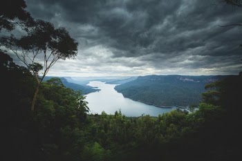 lake surround by mountains under nimbus clouds