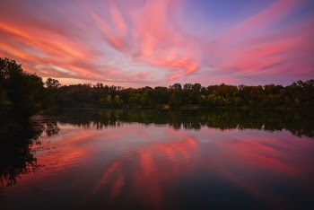 Lake Surrounded With Tall and Green Trees Under Orange and Blue Skies