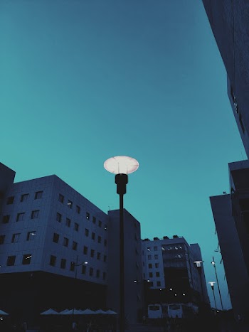 Lamp Posts by the Street Lighted Under Evening Sky