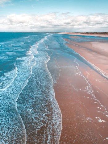 landscape photo of seashore under cloudy sky during daytime