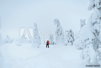 Landscape photographer trekking in a snowy Lapland, Finland