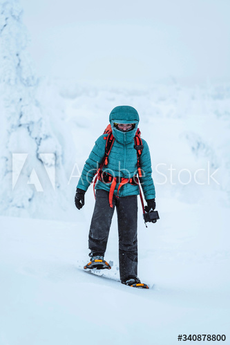 Landscape photographer wearing snowshoes walking in Lapland