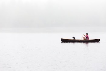 landscape photography man with black dog riding boat on lake