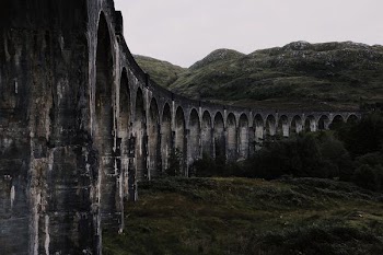 landscape photography of concrete bridge beside green mountain