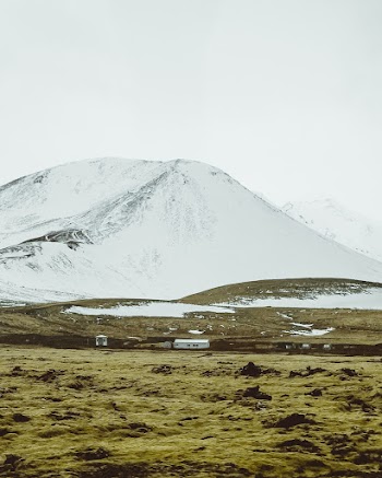 Landscape Photography of Grassland Across Snow Capped Mountain
