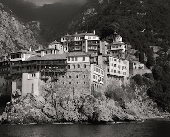 Landscape Photography of Gray and White House Near Mountain Cliffs Above Body of Water