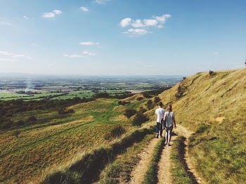 landscape photography of man and woman walking on dirt road