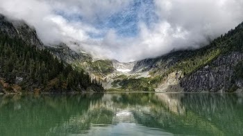 landscape photography of mountain surrounded by pine trees and body of water