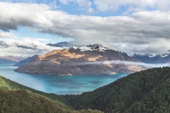 landscape photography of mountain under cloudy sky between body of water at daytime