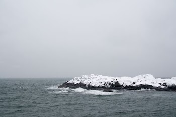 landscape photography of snow-covered rock formation surrounded by body of water