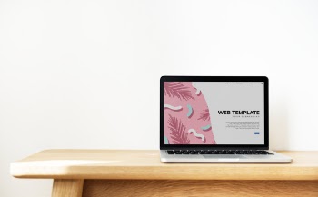 Laptop showing website template on a wooden table Free Psd