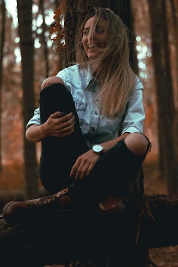 laughing woman leaning on gray tree trunk