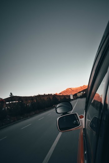 Left Grey Vehicle Side Mirror Reflecting Road