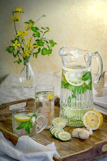 Lemon Juice in Pitcher Beside Glass Up and Sliced Lemons on Serving Tray