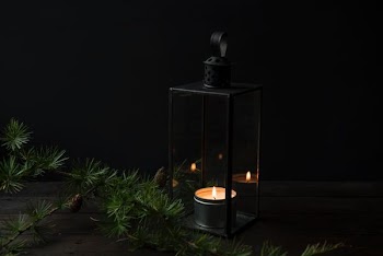 lighted candle inside black lantern holder