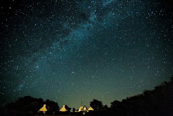 lighted house under sky with stars at night