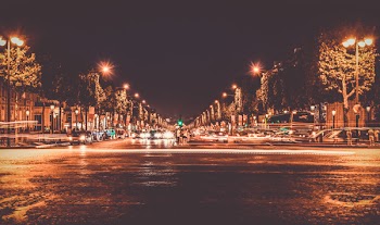Lighted Street With Cars Passing by during Nighttime