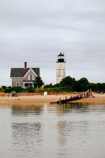 lighthouse near house and body of water during daytime