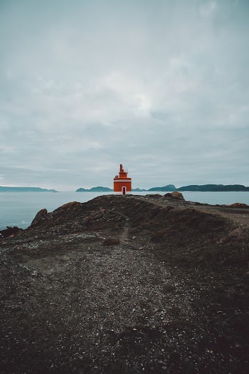 Lighthouse Near Sea Under Cloudy Sky