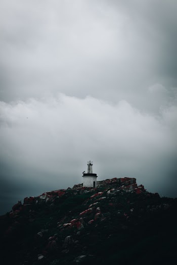Lighthouse on  a Mountain Under Gray Sky