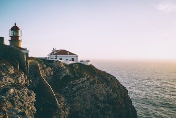 Lighthouse on Cliff Beside Body of Water
