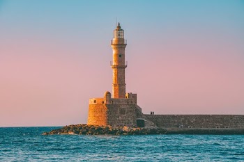 lighthouse with body of water under blue sky during daytime